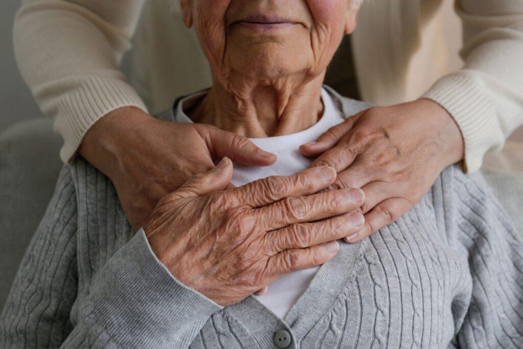 Pflegedienst Guetersloh: Zwei Haende ruhen auf der Brust einer Seniorin und vermitteln Sicherheit im Pflegealltag