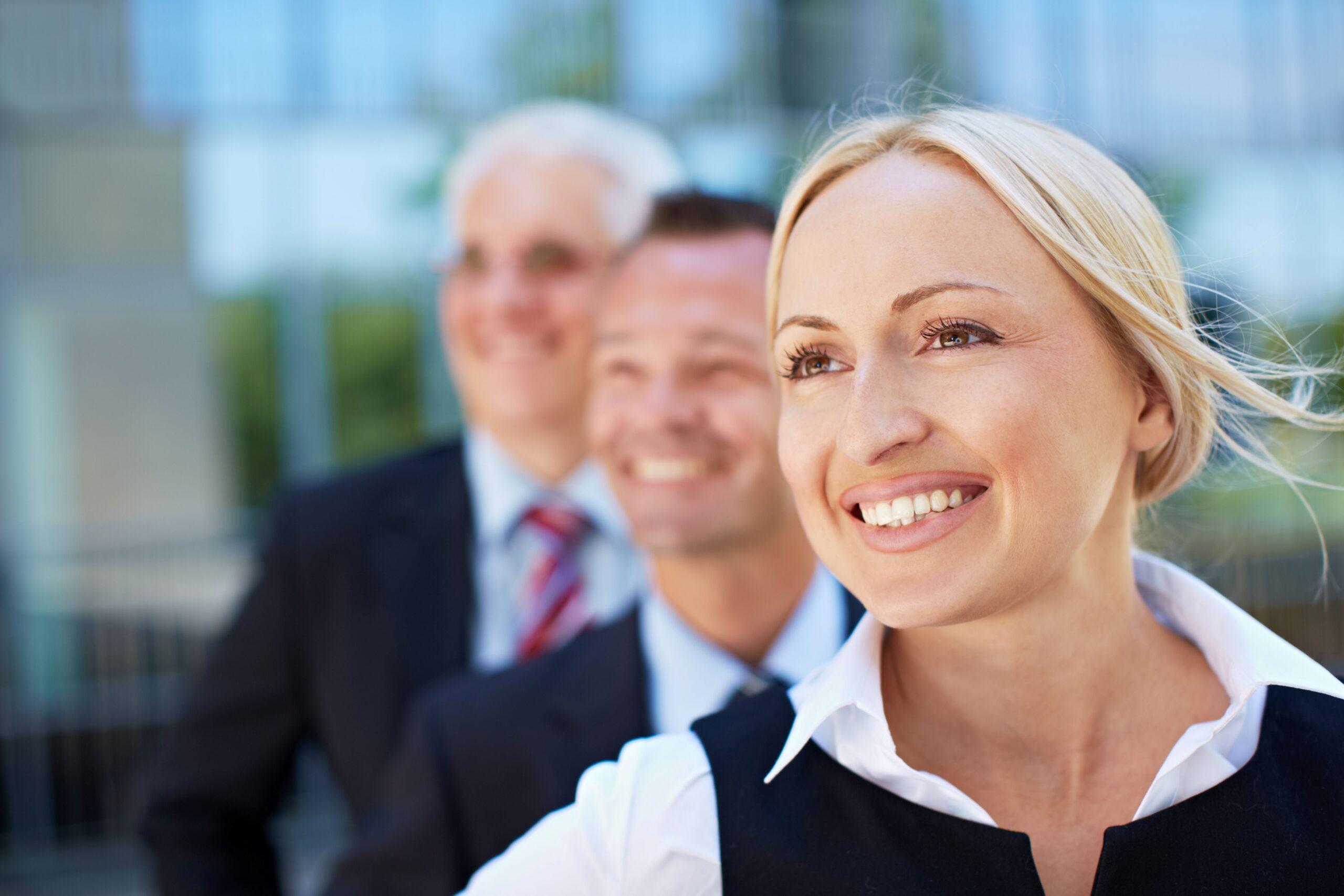 Ferienbetreuung Unternehmen: Zufriedene Berufstätige stehen draußen und lächeln